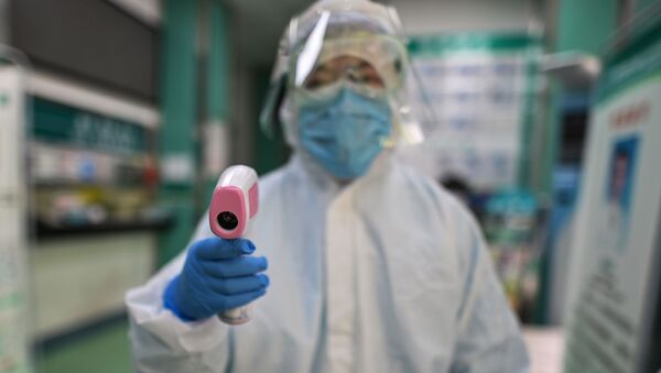 A medical worker prepares to check the temperature of an AFP photojournalist before a COVID-19 coronavirus test in Wuhan in China's central Hubei province on April 16, 2020.  - Sputnik International
