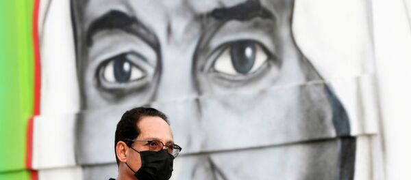 A Saudi man walks past a poster depicting Saudi King Salman bin Abdulaziz, after a curfew was imposed to prevent the spread of the coronavirus disease (COVID-19), in Riyadh, Saudi Arabia March 25, 2020 - Sputnik International