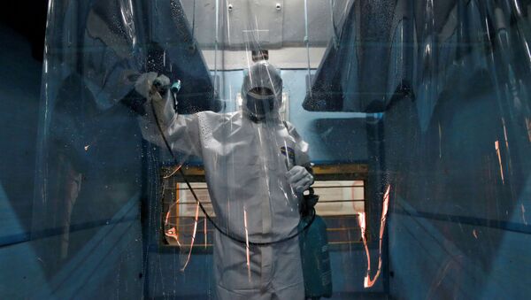 A worker wearing a protective suit disinfects the interior of a passenger train after it was converted into an isolation facility amid concerns about the spread of coronavirus disease (COVID-19), on the outskirts of Kolkata, India, April 6, 2020.  - Sputnik International