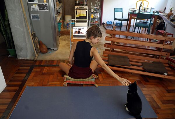Yoga instructor Chris Igreja, 29, pets her cat during an online yoga class she gives from home as a protective measure to prevent the spread of the novel coronavirus disease (COVID-19) outbreak, in Rio de Janeiro, Brazil, 19 March 2020 - Sputnik International