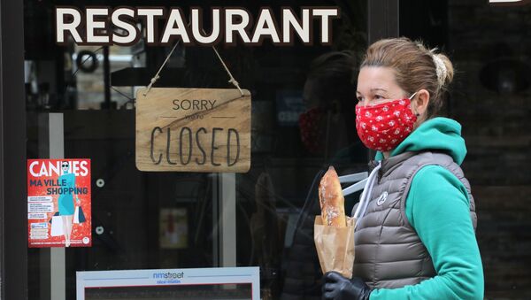 A woman wearing a protective face mask holds a French baguette as she walks past a closed restaurant in Cannes during a lockdown imposed to slow the rate of the coronavirus disease (COVID-19) in France, April 16, 2020 - Sputnik International