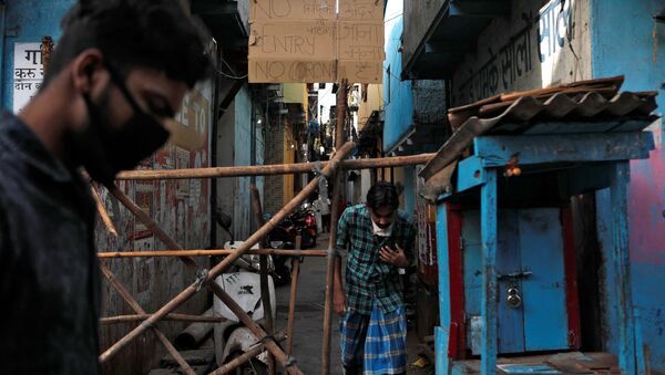 Men walk past a makeshift barricade that was set up to stop people from entering a lane, during a nationwide lockdown in India to slow the spread of COVID-19, in Dharavi, one of Asia's largest slums, during the coronavirus disease outbreak, in Mumbai, India, April 9, 2020 - Sputnik International