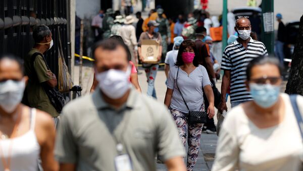 People wearing protective masks walk on a street during a nationwide quarantine as the spread of the coronavirus disease (COVID-19) continues, in Caracas, Venezuela April 20, 2020. - Sputnik International