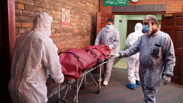 Workers wearing protective equipment transport a body in the grounds of the Central Jamia Mosque Ghamkol Sharif, a temporary morgue set up at a Mosque as the spread of the coronavirus disease (COVID-19) continues, Birmingham, Britain, April 21, 2020. - Sputnik International