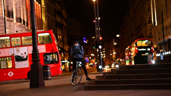 A delivery cyclist checks his phone in Piccadilly Circus during the late evening, as the city at night is deserted like never before while the coronavirus disease (COVID-19) lockdown continues, in London, Britain April 21, 2020 - Sputnik International