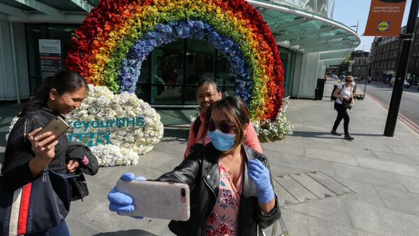 People take a selfie outside University College Hospital next to a rainbow flower display which was organised by the hospital workers to say thank you to the people for their support, during the outbreak of the coronavirus disease (COVID-19) in London, Britain, April 24, 2020.    - Sputnik International