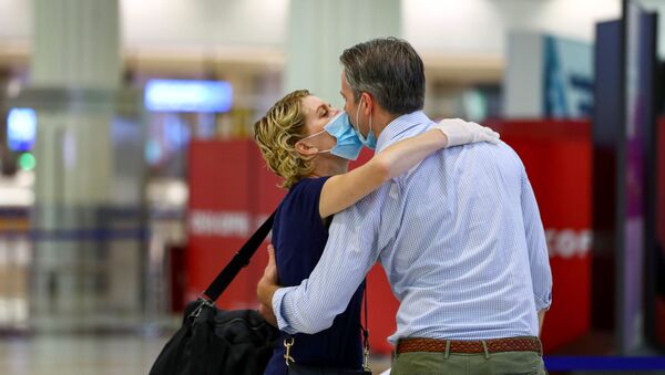 A man wearing a protective mask kisses his wife before she boards a plane at Dubai International Airport, as Emirates airline resumed limited outbound passenger flights amid the COVID-19 pandemic in Dubai, UAE, 27 April 2020 - Sputnik International