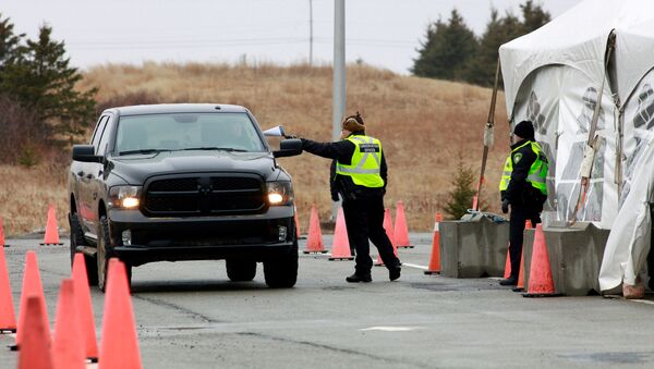 A Nova Scotia conservation officer passes a paper to a person crossing into the province from New Brunswick in its effort to prevent the spread of the coronavirus disease (COVID-19) at the Fort Lawrence, Canada April 2, 2020. - Sputnik International