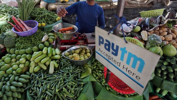 FILE PHOTO: A vendor weighs vegetable next to an advertisement of Paytm, a digital payments firm, hanging amidst his vegetables at a roadside market in Mumbai, India, April 2, 2019 - Sputnik International