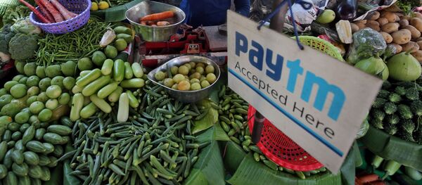 FILE PHOTO: A vendor weighs vegetable next to an advertisement of Paytm, a digital payments firm, hanging amidst his vegetables at a roadside market in Mumbai, India, April 2, 2019 - Sputnik International