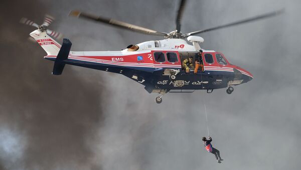 A resident (bottom) is surrounded by smoke as he is winched up to a rescue helicopter from an apartment building which caught fire in Uijeongbu, north of Seoul, on January 10, 2015 - Sputnik International