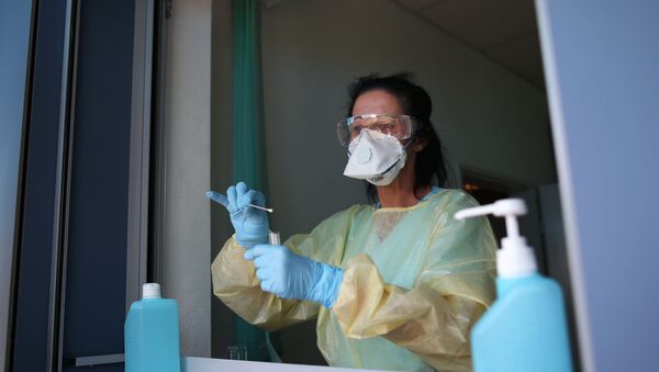 Nurse Sylke Pflugmacher takes a sample at a testing point for medical staff members at the community hospital in Magdeburg, eastern Germany, on April 16, 2020 during the novel coronavirus COVID-19 pandemic. - Sputnik International