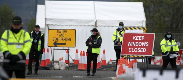 Staff direct traffic as key workers arrive for a test for the novel coronavirus Covid-19 at a drive-in testing centre at Glasgow Airport on April 29, 2020, as the UK continues in lockdown to help curb the spread of the coronavirus. - Sputnik International