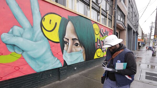 A postal carrier walks past a mural on a business closed during the coronavirus outbreak Saturday, May 2, 2020, in Seattle. - Sputnik International