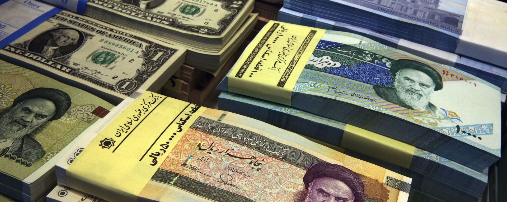 In this 4 April 2015 file photo, Iranian and U.S. banknotes are on display at a currency exchange shop in downtown Tehran, Iran. Iran's president has sent a bill to Parliament that would cut four zeroes from the value of the nation's sanctions-battered currency, the rial. Semi-official news agencies reported the news on Wednesday, 21 August 2019, saying President Hassan Rouhani sent the bill with urgency to the Parliament to consider. Iran's rial has been hammered by the effects of increasing US sanctions on the country. - Sputnik International, 1920, 13.10.2020