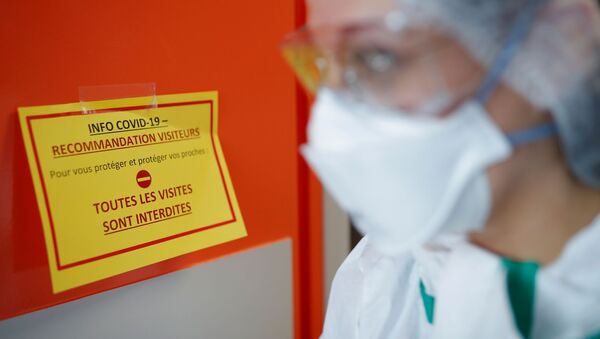A nurse, wearing protective gear and face mask, walks past an information sign at the post COVID-19 unit of the Clinique Breteche private hospital in Nantes during the outbreak of the coronavirus disease (COVID-19) in France, April 30, 2020.  - Sputnik International