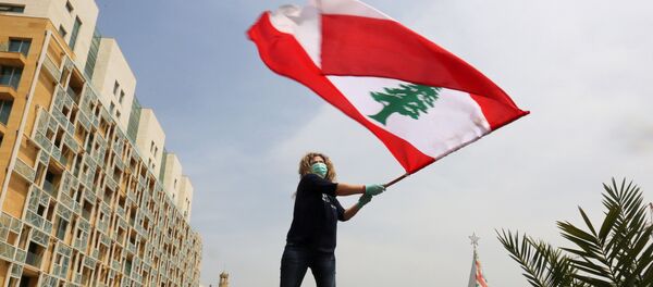An anti-government demonstrator holds a Lebanese flag as she stands on top of her car, during a countrywide lockdown to combat the spread of the coronavirus disease (COVID-19), in Beirut, Lebanon April 21, 2020. An anti-government demonstrator holds a Lebanese flag as she stands on top of her car, during a countrywide lockdown to combat the spread of the coronavirus disease (COVID-19), in Beirut, Lebanon April 21, 2020. - Sputnik International