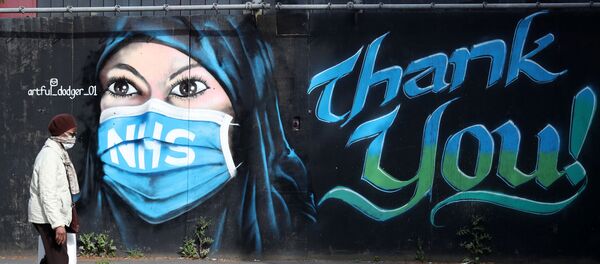 A person wearing a protective face mask walks past streetart ‘NHS Dedication Mural’ by The Artful Dodger (A.Dee) in Elephant & Castle, following the outbreak of the coronavirus disease (COVID-19), London, Britain, May 5, 2020 - Sputnik International