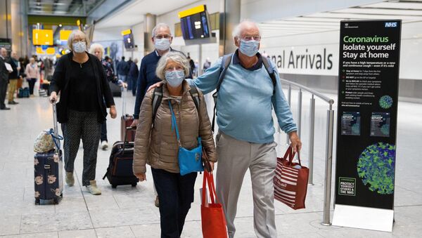Travellers who had been aboard the Braemar cruise ship, operated by Fred Olsen Cruise Lines, and wearing face masks as a precautionary measure against covid-19, react as they arrive at Heathrow Airport in London on March 19, 2020, after being flown back from Cuba. - Sputnik International