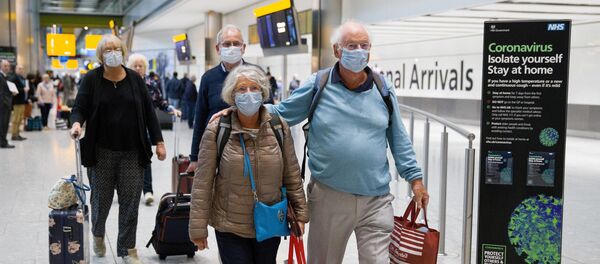 Travellers who had been aboard the Braemar cruise ship, operated by Fred Olsen Cruise Lines, and wearing face masks as a precautionary measure against covid-19, react as they arrive at Heathrow Airport in London on March 19, 2020, after being flown back from Cuba. - Sputnik International