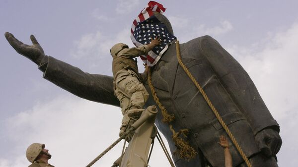 In this file photo taken Wednesday, April 9, 2003, an Iraqi man, bottom right, watches Cpl. Edward Chin of the 3rd Battalion, 4th Marines Regiment, cover the face of a statue of Saddam Hussein with an American flag before toppling the statue in downtown in Baghdad, Iraq. - Sputnik International