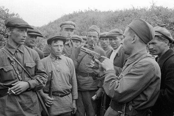 The commander of a partisan detachment shows weapons to fighters. Smolensk region, the USSR, 1941 - Sputnik International