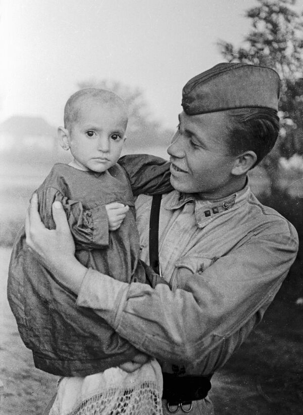 A Soviet officer (right) holds a girl saved from the village of Elkhotovo, 1942 - Sputnik International