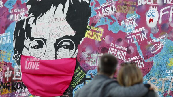 A couple look at the Lennon Wall with a face mask attached to the image of John Lennon, in Prague, Czech Republic, Monday, April 6, 2020.  - Sputnik International