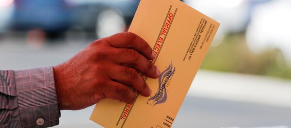 An election worker places a mail-in ballot into an election box at a drive-through drop off location at the Registrar of Voters in San Diego, California, U.S. November 5, 2018 - Sputnik International