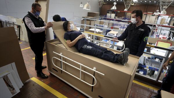 Rodolfo Gomez, left, and his employees demonstrate how their design of a cardboard box can serve as both a hospital bed and a coffin - Sputnik International