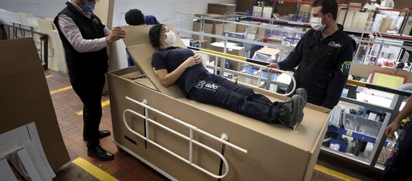 Rodolfo Gomez, left, and his employees demonstrate how their design of a cardboard box can serve as both a hospital bed and a coffin - Sputnik International