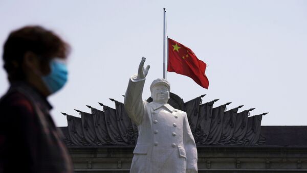 The Chinese national flag flies at half-mast behind a statue of late Chinese chairman Mao Zedong in Wuhan, Hubei province, as China holds a national mourning for those who died of the coronavirus disease (COVID-19), on the Qingming tomb-sweeping festival, April 4, 2020 - Sputnik International