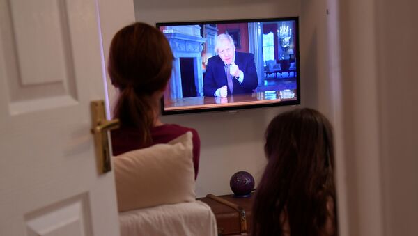 Family members in a house in London watch Britain's Prime Minister Boris Johnson on television during a broadcast to outline plans for gradually easing lockdown measures following the outbreak of the coronavirus disease (COVID-19), London, Britain, May 10, 2020   - Sputnik International