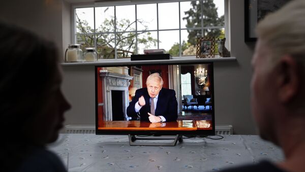 A family gather around the television to watch Britain's Prime Minister Boris Johnson give a televised message to the nation in Hartley Wintney, west of London on May 10, 2020, as the government sets out it's roadmap to ease the national lockdown due to the novel coronavirus COVID-19 pandemic. - Sputnik International