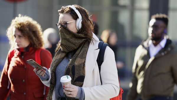 A commuter covers her face in London, Monday, March 16, 2020. For most people, the new coronavirus causes only mild or moderate symptoms, such as fever and cough. For some, especially older adults and people with existing health problems, it can cause more severe illness, including pneumonia. - Sputnik International