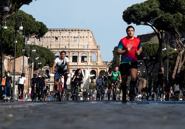 People jog or ride along Via dei Fori Imperiali in central Rome on 10 May 2020 during the country's partial lockdown aimed at curbing the spread of the COVID-19 infection, caused by the novel coronavirus.  - Sputnik International