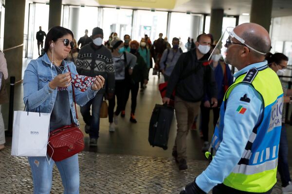 A police officer asks a woman to put on her protective mask, as the country eases the lockdown due to the spread of the coronavirus disease (COVID-19), at Cais do Sodre station in Lisbon, Portugal 4 May 2020.  - Sputnik International