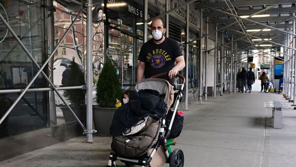 A man wearing a protective mask pushes a child wearing a protective mask in a stroller during the coronavirus pandemic on April 12, 2020 in New York City. - Sputnik International