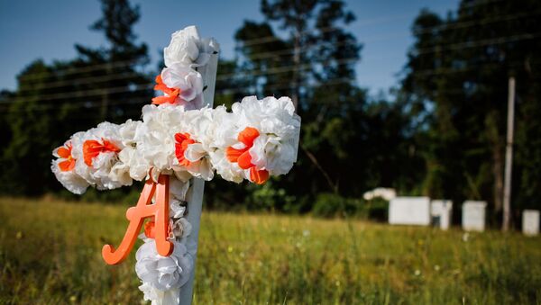 A white and orange cross with an A on it stands stuck in the ground along highway 17 at the entrance of the Satilla Shores neighbourhood where Ahmaud Arbery, an unarmed young black man, was shot after being chased by a white former law enforcement officer and his son, at the Glynn County Courthouse in Brunswick, Georgia, U.S., May 8, 2020 - Sputnik International