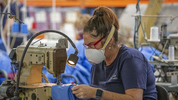 A worker wears a protective face mask as she makes scrubs for front-line National Health Service (NHS) staff in O'Neills sportswear factory in Strabane in Northern Ireland on March 26, 2020.  - Sputnik International