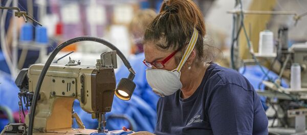 A worker wears a protective face mask as she makes scrubs for front-line National Health Service (NHS) staff in O'Neills sportswear factory in Strabane in Northern Ireland on March 26, 2020. A worker wears a protective face mask as she makes scrubs for front-line National Health Service (NHS) staff in O'Neills sportswear factory in Strabane in Northern Ireland on March 26, 2020. - Sputnik International
