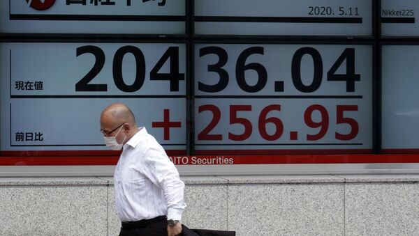 A man wearing a face mask  walks past an electronic stock board showing Japan's Nikkei 225 index at a securities firm in Tokyo Monday, May 11, 2020 - Sputnik International