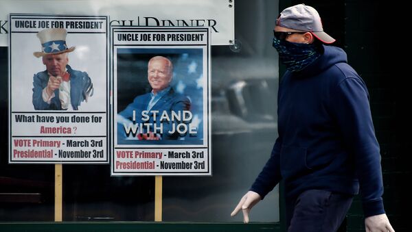 A man wearing a face mask walks past signs for Joe Biden's 2020 presidential campaign amid the coronavirus outbreak on May 11, 2020 in Alexandria, Virginia - Sputnik International