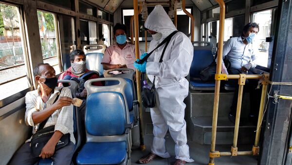 A bus conductor wearing a protective gear issues tickets to passengers maintaining safe social distance on the bus, after the state government resumed public bus service on limited routes after nearly seven-week lockdown to slow the spreading of the coronavirus disease (COVID-19), in Kolkata, India, May 14, 2020. - Sputnik International