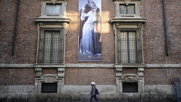 A woman walks past a poster depicting the 1859 painting by Italian artist Francesco Hayez, ll Bacio (The Kiss), hanging on a facade of the Pinacoteca di Brera Museum, in Milan, Italy, Wednesday, March 11, 2020. - Sputnik International