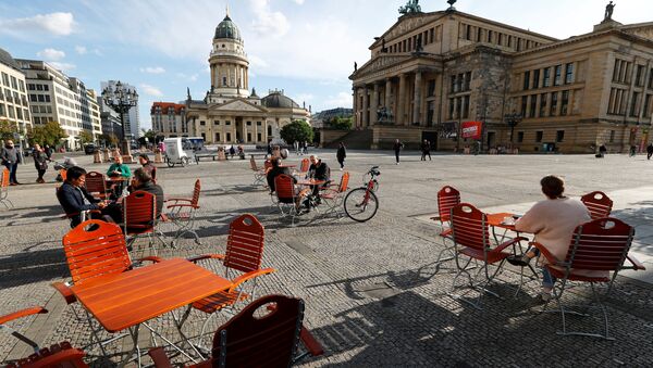 Люди наслаждаются погодой в кафе на площади Жандарменмаркт в Берлине, соблюдая принцип социальной дистанции - Sputnik International