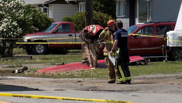 Fire officials talk in a residential neighbourhood street in front of the tail wreckage from a Royal Canadian Air Force Snowbirds jet after a member of the exhibition team crashed shortly after takeoff in Kamloops, British Columbia, Canada May 17, 2020. - Sputnik International