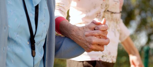 Resident Enid Roche takes a walk in the grounds of Foxholes Care Home, assisted by activities director Susan Davies as the spread of the coronavirus disease (COVID-19) continues, Hitchin, Britain, 25 March 2020. - Sputnik International