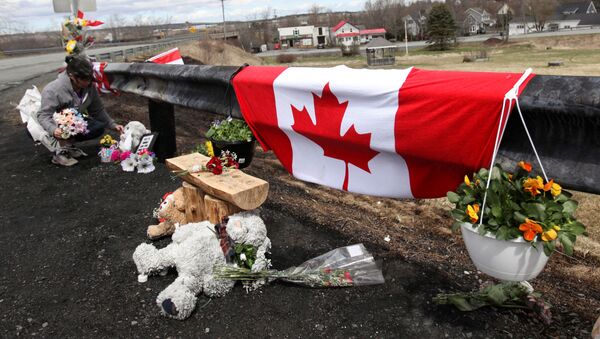Krista Hughes adjusts flowers that had blown away from a makeshift memorial for Royal Canadian Mounted Police (RCMP) Constable Heidi Stevenson, who was shot dead during Sunday's killing spree that worked it's way across several Nova Scotian communities, in Shubenacadie, near Enfield, Nova Scotia, Canada April 22, 2020. - Sputnik International