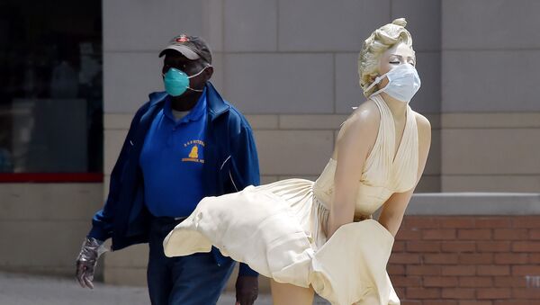 A man wearing a face mask walks past The Forever Marilyn statue by Seward Johnson,  which is also wearing a mask amid the Coronavirus outbreak in National Harbor, Maryland on 11 May 2020.  - Sputnik International